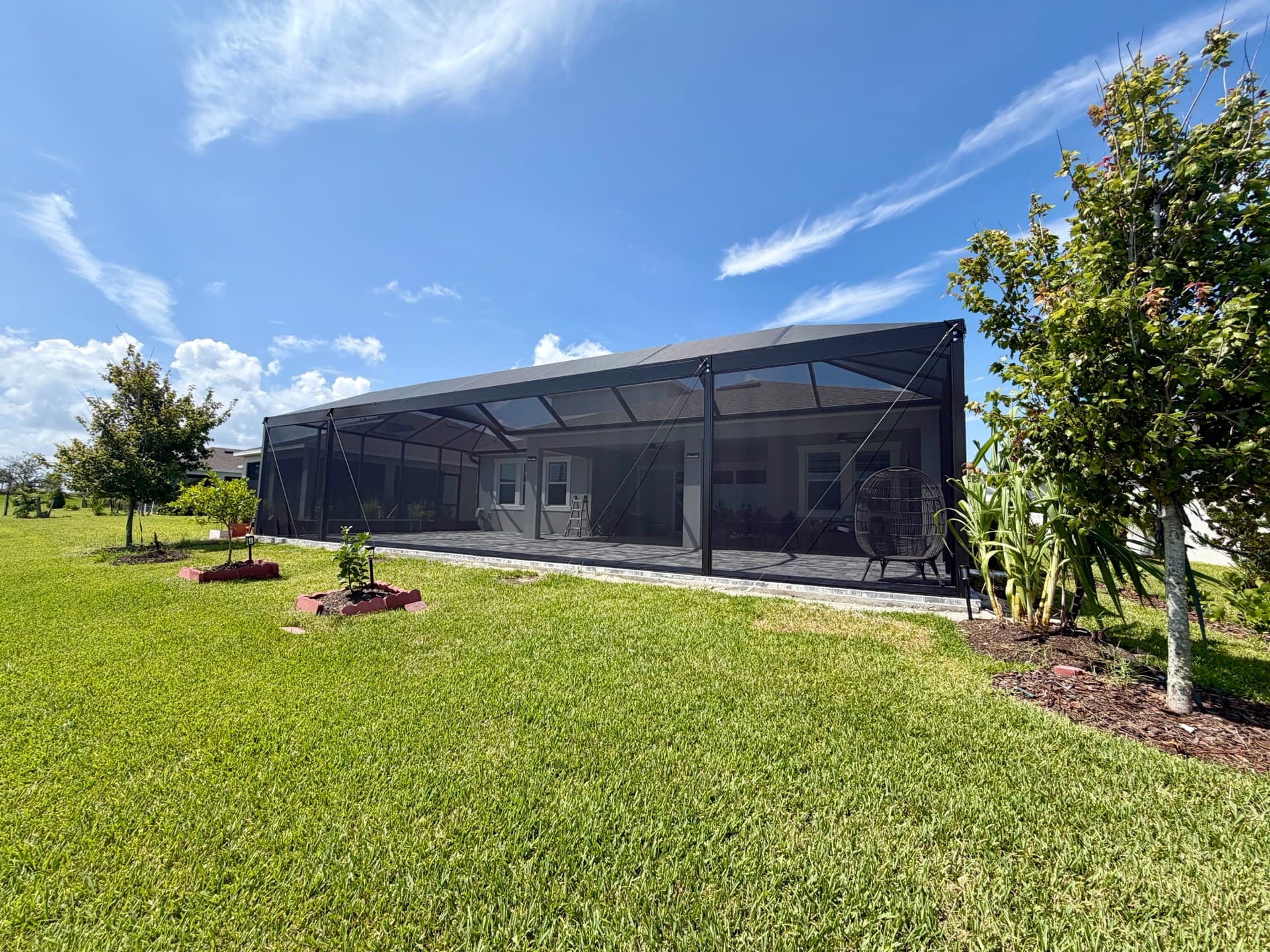 Panoramic screen enclosure with bronze framing spanning a lakefront patio on a Florida home